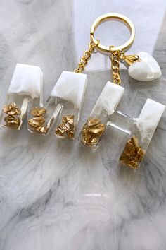 four pieces of gold and white material on a marble surface with a keychain