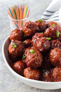 a white bowl filled with meatballs next to a colorful straw and napkin on the table