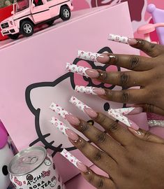 a woman's hands with pink and white nail polish on her nails next to a hello kitty box