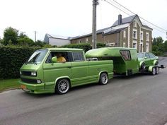 a green van is pulling a trailer behind it