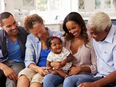 a group of people sitting on top of a couch next to each other holding a baby