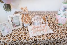 a table topped with cake pops and giraffes on top of a leopard print cloth