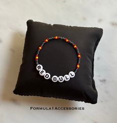 Embrace the thrill of Formula One racing with this Red Bull beaded bracelet, featuring the iconic team's signature colors! 🏆 Perfect for fans of Formula 1! The bracelet is made of strong elastic string, small glass beads and white letter beads. Feel free to message us if you have questions or need variations. Our bracelets ship from Norway and they are sent as letters without tracking. Any additional tax that may apply is the responsibility of the customer. If you are unsure about possible taxe Trendy Red Beaded Bracelet With Letter Beads, Sporty Red Adjustable Wristband, Adjustable Red Sporty Wristband, Trendy Red Personalized Beaded Bracelets, Trendy Personalized Red Beaded Bracelets, Personalized Red Trendy Beaded Bracelets, Sporty Red Wristband For Sports Events, Adjustable Red Name Bracelet With Round Beads, Red Sporty Wristband For Sports Events