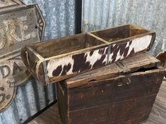 two old wooden boxes sitting next to each other on top of a wood floor in front of a metal wall