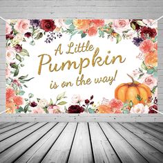 a white brick wall with an orange pumpkin and flowers on it that says, a little pumpkin is on the way