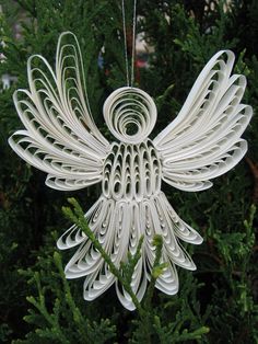 an ornament made out of white paper hanging from a tree