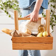 a person holding a wooden crate filled with food