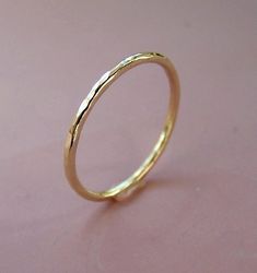 a close up of a gold ring on a pink surface