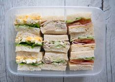 a plastic container filled with sandwiches on top of a wooden table