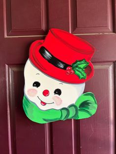 a red door with a painted snowman's hat and green scarf on it