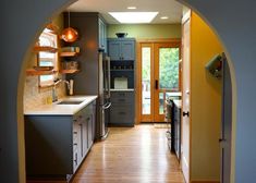 an archway leading into a kitchen with stainless steel appliances and wood flooring on the walls