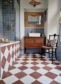 a bathroom with a checkered tile floor and wooden cabinet in the corner, along with a chair