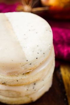 a stack of three white donuts sitting on top of a wooden table next to a pink towel