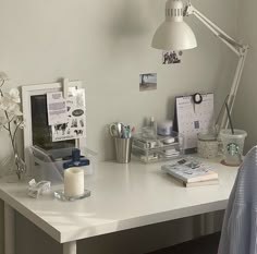 a white desk topped with a lamp next to a mirror and other office supplies on top of it