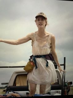 a woman standing in the back of a pick up truck with her arms out and hands outstretched