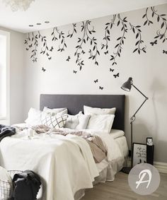 a bedroom with white walls and black butterflies on the wall, along with a bed