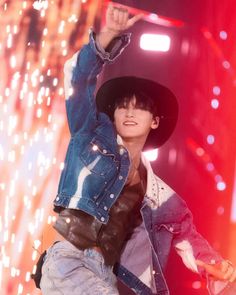 a male in a blue jacket and hat is dancing on stage with fireworks behind him