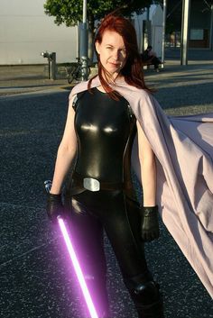 a woman dressed in black and holding a purple light saber