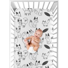 a baby in a white crib with black and white foxes on it's back