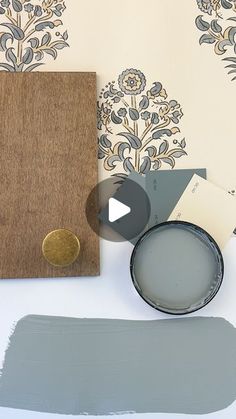 some paint samples are sitting on a table next to a wooden frame and wallpaper