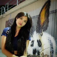 a woman standing in front of a wall with a panda painting on it's side