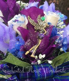 purple and white flowers are arranged in a bouquet with an insect brooch on it