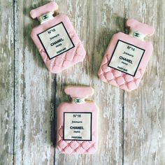 three cookies shaped like chanel perfume bottles on a wooden table with the words chanel printed on them