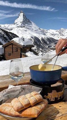 a person is preparing food on a table with mountains in the background and snow covered ground