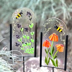 two glass vases with flowers and bees on them