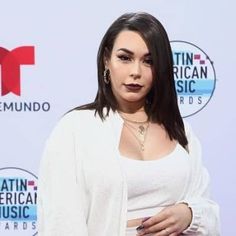 a woman in white shirt and skirt standing on red carpet with her hand on her hip