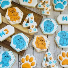 cookies decorated with cartoon characters and paw prints on a wooden table next to cookie cutters