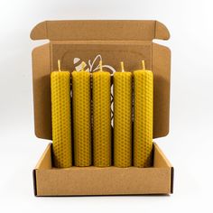 four yellow candles are in a cardboard box