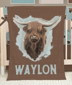 a baby crib with a brown and white blanket that has an image of a bison on it