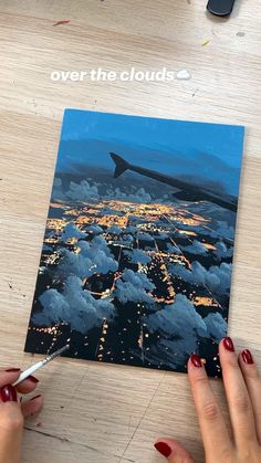 a woman is painting an airplane over the clouds at night with red nail polish on her nails