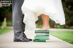 a bride and groom standing next to each other with their feet on top of books