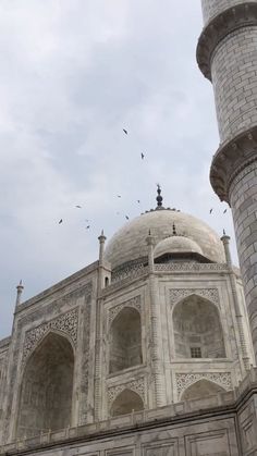 birds fly over the top of an ornate building with two minarets on each side