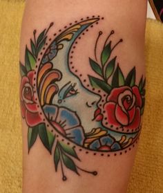 a tattoo on the leg of a woman with flowers and a crescent moon in it