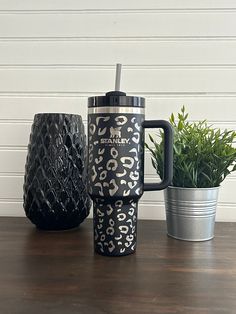 two mugs sitting on top of a table next to a potted green plant