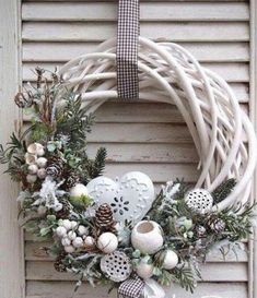 a christmas wreath hanging on the side of a door with pine cones and other decorations