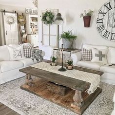 a living room filled with white couches and wooden tables in front of a large clock