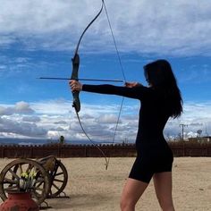 a woman with long black hair is holding a bow and arrow