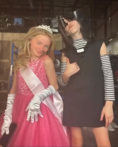 two girls dressed up in costumes posing for the camera with one girl wearing a tiara