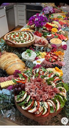 an assortment of food is displayed on a long table with breads and salads