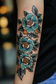 a woman's arm with blue flowers on it and green leaves around the wrist