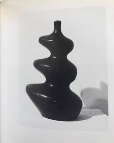 a black vase sitting on top of a table next to a white object in the background