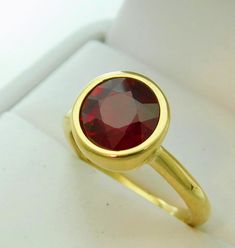 Gemstone: Ruby Treatments: Glass-filled Diameter: 9mm Weight: 4.16 carats Color: As shown. Blue Clarity: Eye clean, no visible surface blemishes. Cut: Round Brilliant Cut Origin: Brazil Metal: 14K Yellow Gold. Available in 14K white and 14K rose gold at no additional charge. (Also available in Platinum, 18K Rose 18K white - additional charge for upgrade) Weight: 6.5 grams of 14K gold. Weight will vary with ring size ordered. Ring Sizes: Available in all sizes 4 thru 10 Larger sizes up to 12 for Couple Comics, Ruby Rings, Bezel Set Ring, Set Ring, Bezel Setting, Gemstone Colors, Rings Statement, Green And Gold, Statement Rings