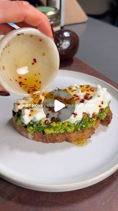 someone is pouring sauce on a piece of bread with avocado and other toppings