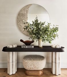 a table with a mirror and vase on top of it next to a plant in a vase