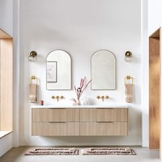 a bathroom with two sinks and mirrors on the wall next to a rug in front of it