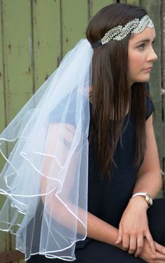 a woman wearing a veil and sitting on a bench with her hair in a bun